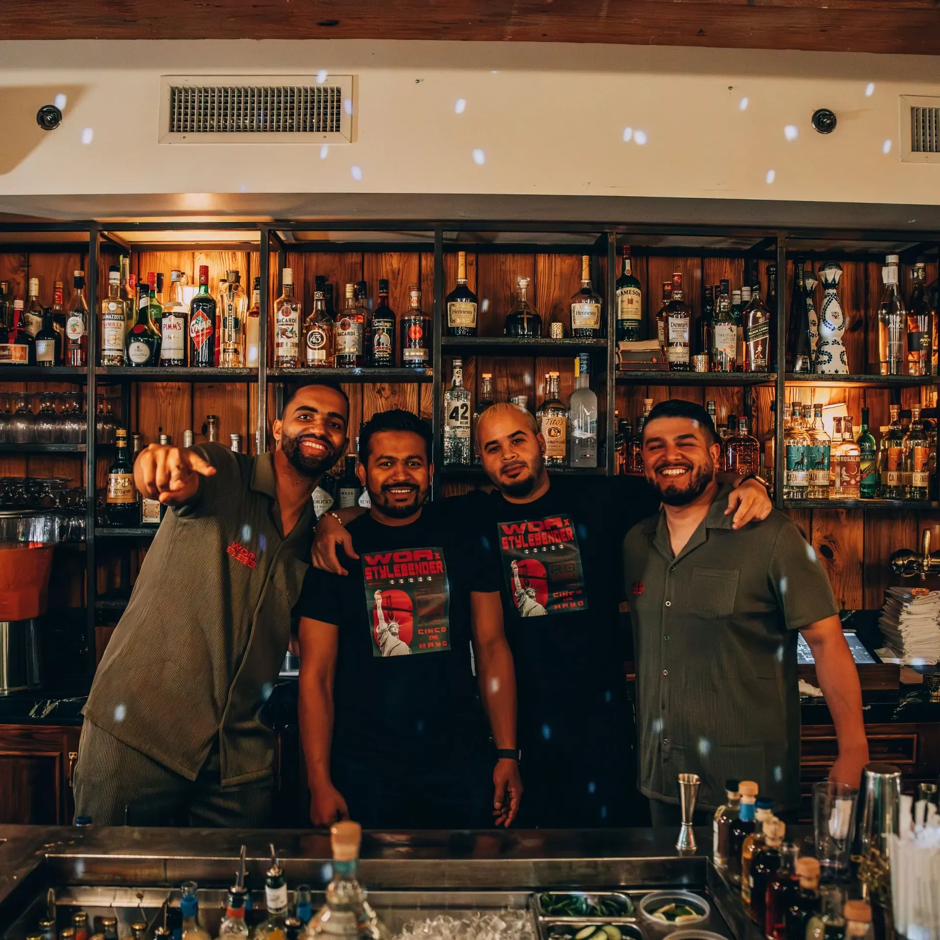The WOA crew in custom shirts behind a venue's bar during a takeover