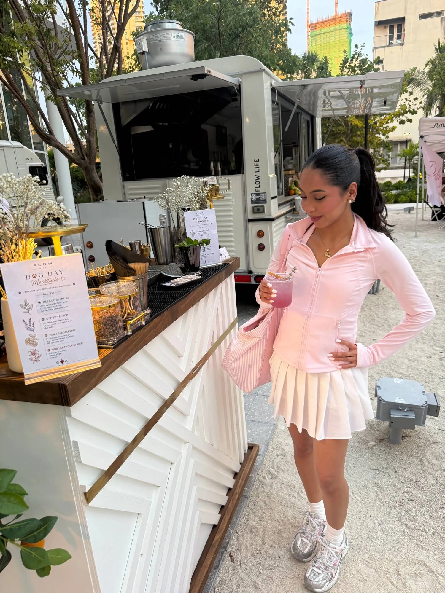 A guest with a cocktail beside a white WOA bar at an outdoor activation